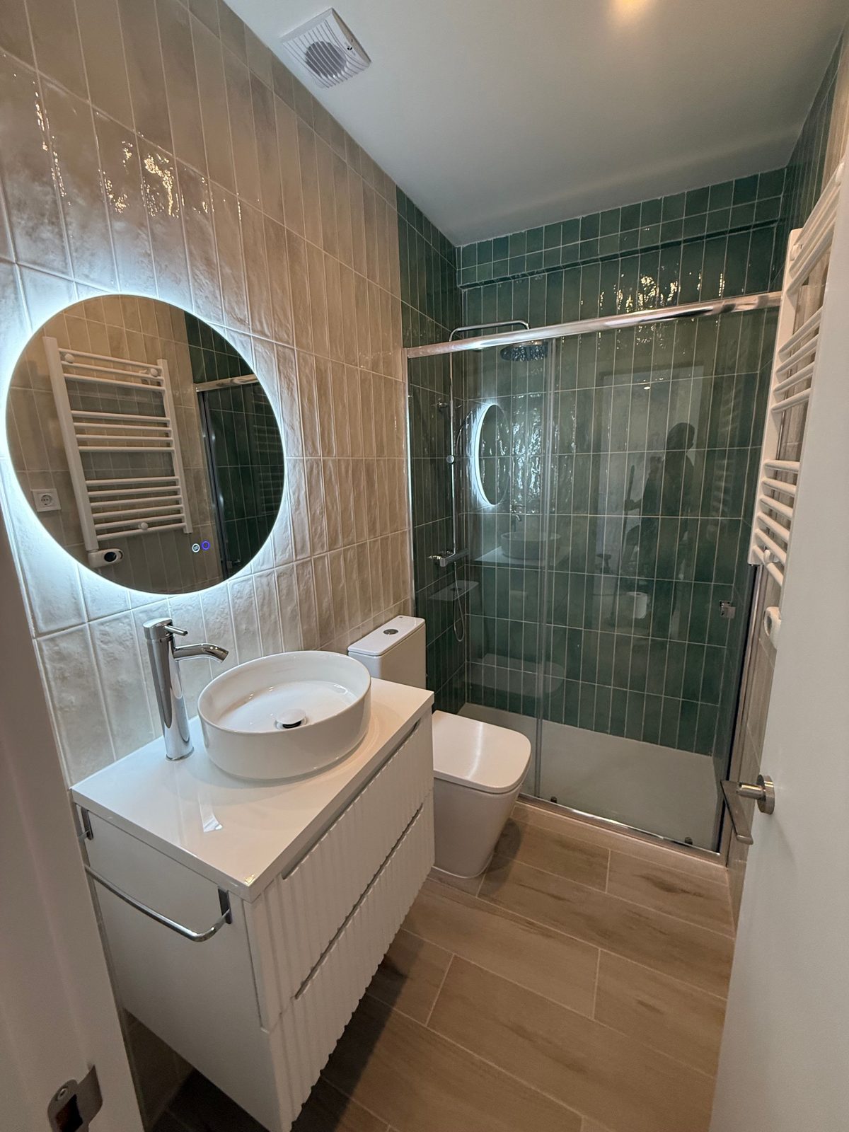 Baño reformado con azulejo verde y plato de ducha